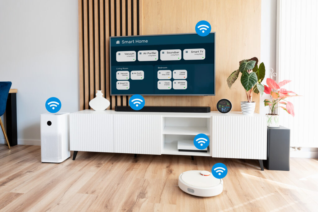 Ein Bild, das viele IoT-Geräte im Privathaushalt zeigt. Es zeigt ein Zimmer mit Holzboden, darauf steht ein Lufterfrischer, ein Sideboard, darüber ein Smart-Homefähiger Fernseher, eine Soundleiste, und ein Staubsaugerroboter reinigt gerade.